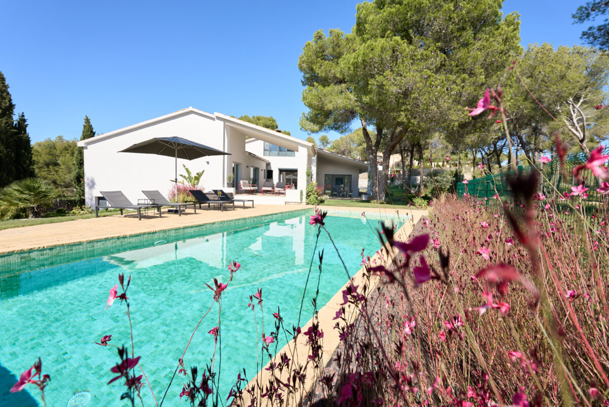 Swimming pool, sunloungers and flowering garden beside the white Casa Brisa guesthouse near Sitges