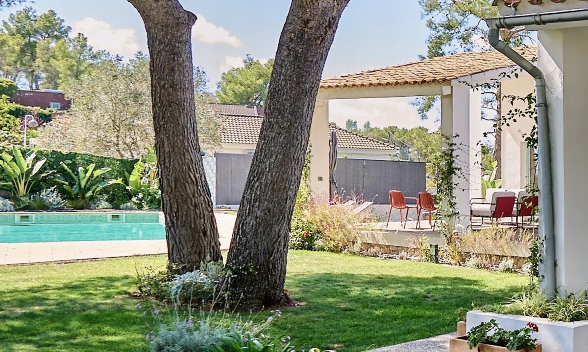 Tree-lined lawn and garden beside the swimming pool and covered terrace at Casa Brisa near Sitges